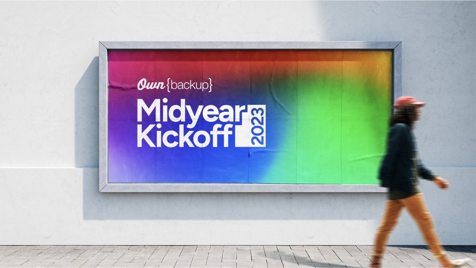 Rainbow gradient Midyear Kickoff 2023 billboard with a person walking past