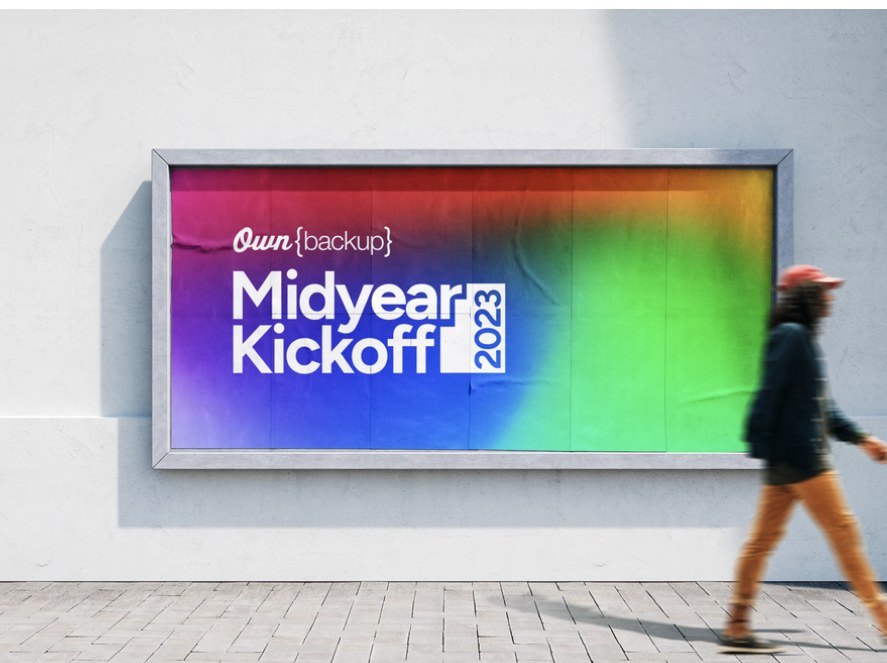 Rainbow gradient Midyear Kickoff billboard with a person walking past